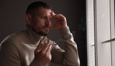 Odada sigara içen bir adam var.