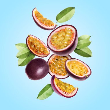 Lezzetli olgun tutku meyveleri ve açık mavi arka plana düşen yeşil yapraklar.