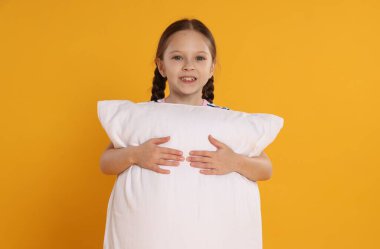 Turuncu arka planda yastığı olan tatlı bir kız.