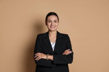 Bej arka planda takım elbiseli kendine güvenen bir iş kadını.