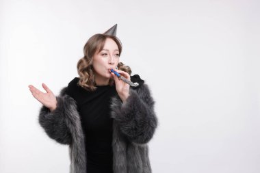 Doğum günü kutlaması. Beyaz arka planda parti kornası çalan bir kadın. Metin için boşluk