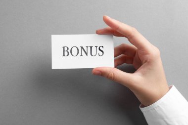 Gri masada elinde kelime bonusu olan bir kadın var.