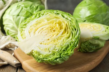 Taze lahanalar, ağ torbası ve bıçak ahşap masada, yakın plan.