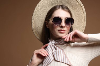 Kahverengi arka planda şık giyinmiş güzel bir kadının moda portresi.