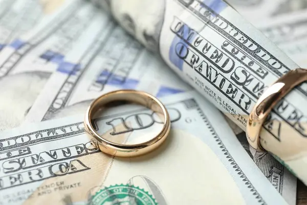 Altın alyanslar ve dolar banknotları, yakın plan.