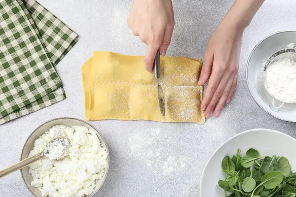 Işık masasında ravioli kesen kadın, üst manzara.