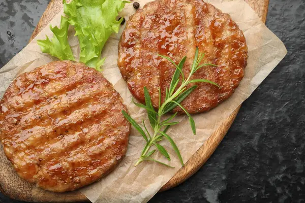 Lezzetli hamburger köfteleri ve baharatlar siyah masada, üst tarafta.