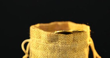 Siyah arkaplanda çuval bezi içine madeni paralar dökülüyor.