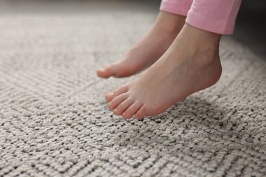 Evdeki gri halıdaki kız, yakın plan.