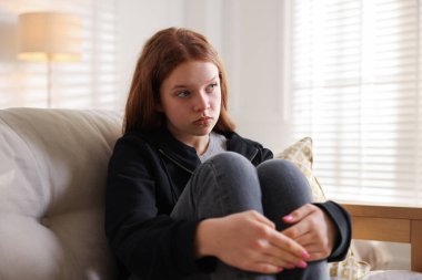 Evdeki kanepede oturan üzgün genç kız.