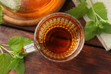Cam bardakta Aromatik limon merhemi çayı, çaydanlık ve taze yapraklar ahşap masada, düz yerde.