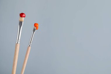 Açık gri arkaplanda renkli iki fırça, yakın plan. Metin için boşluk