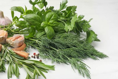 Beyaz masada farklı taze otlar ve baharatlar, yakın plan.