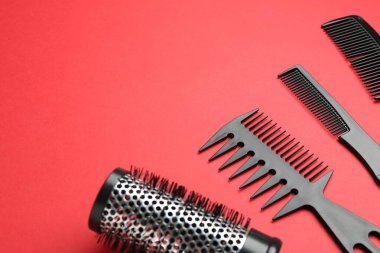 Kırmızı arka planda farklı kuaför aletleri, yakın plan. Metin için boşluk