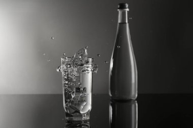 Tatlı su, cam parçalarından yansıyor ayna masasında, gri arka planda.