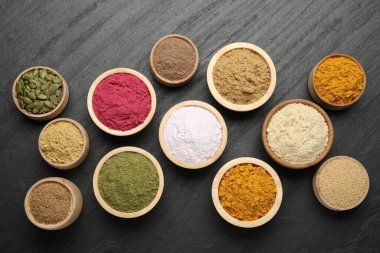 Siyah masa üzerinde farklı süper yiyecek tozları, düz uzanmış.