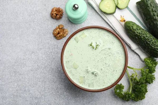 Lezzetli salatalık çorbası ve açık gri masadaki malzemeler. Metin için boşluk