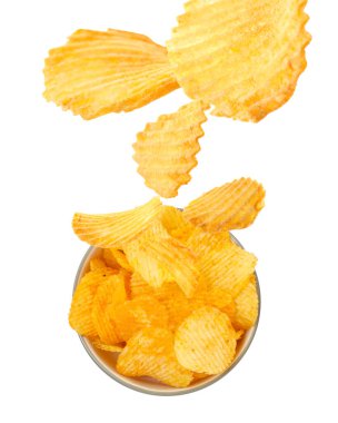 Lezzetli patates cipsleri beyaz arka planda kaseye düşüyor.