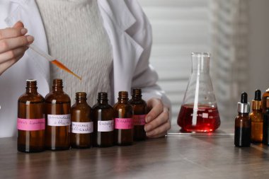 Laboratuardaki ahşap masada lüks parfüm üreten profesyonel parfümcü.