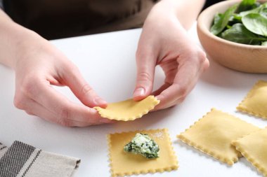 Beyaz masada peynirli ve ıspanaklı ravioli yapan kadın, yakın plan.