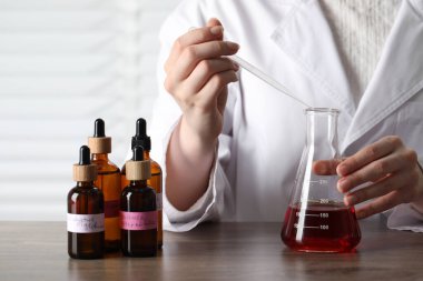 Laboratuardaki ahşap masada lüks parfüm üreten profesyonel parfümcü.