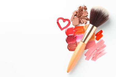 Beyaz arka planda farklı kozmetik ürünleri ve makyaj fırçası var. Metin için boşluk