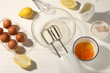 El çırpıcı, kasede yumurta beyazı, beyaz ahşap masa üzerinde yumurta ve diğer ürünler, düz konum