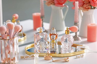 Farklı parfüm şişeleri, aksesuarlar ve çiçekler kapalı salonda.