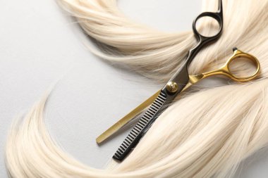 Sarı saç tokası ve makas açık gri arka planda, yakın plan.