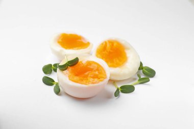 Beyaz zemin üzerinde mikro yeşillikler olan yumuşak haşlanmış yumurtalar.