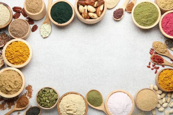 Açık gri masadaki farklı süper yiyecek tozlarının çerçevesi düz. Metin için boşluk