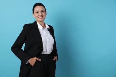 Açık mavi arka planda takım elbiseli kendine güvenen bir iş kadını. Metin için boşluk