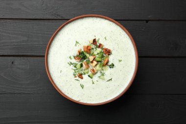 Siyah ahşap masada dereotlu ve cevizli lezzetli salatalık çorbası.