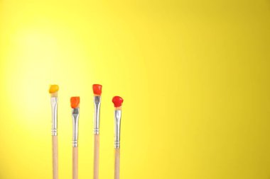 Sarı arka planda birçok renkli fırça, yakın plan. Metin için boşluk