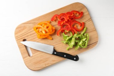 Taze renkli dolmalık biber dilimleri ve beyaz ahşap masa üzerinde bıçak.