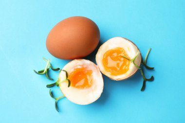 Hafif kaynamış yumurta ve açık mavi arka planda mikro yeşiller, üst manzara.