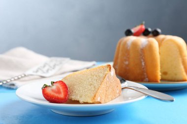 Açık mavi ahşap masada pudra şekerli ve dutlu Lezzetli kek, yakın plan.