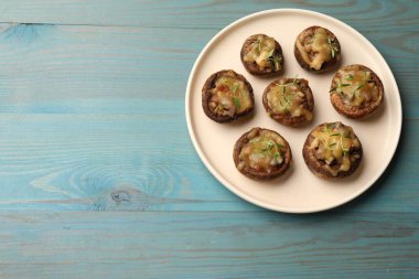 Eritilmiş peynirli lezzetli mantarlar ve açık mavi ahşap masa üzerinde kekik. Metin için boşluk