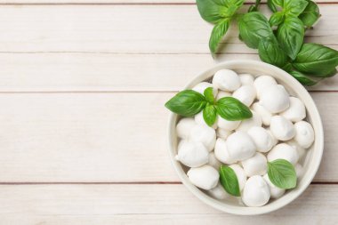 Lezzetli mozzarella peynir topları kasede ve fesleğen açık ahşap masada, düz yerde. Metin için boşluk