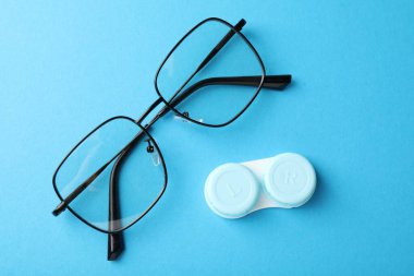 Kontak lens kutusu ve açık mavi zemin üzerindeki gözlükler, düz konum