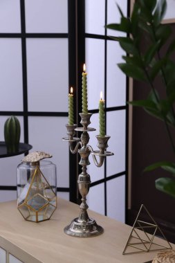 Kahverengi duvarın yanında yanan mumlar ve dekorlarla süslü zarif bir şamdan.
