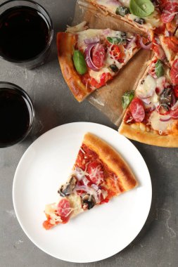 Gri masada servis edilen ince tütsülenmiş sosisli lezzetli bir pizza.