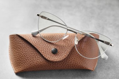 Gri masada şık gözlükleri olan bir çanta, yakın plan.