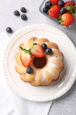 Pudra şekerli ve böğürtlenli lezzetli kek açık gri masada, düz yatıyordu.