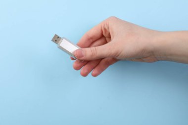 Flaş belleği açık mavi arkaplanda tutan kadın, yakın plan.