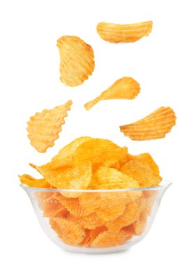 Lezzetli patates cipsleri beyaz arka planda kaseye düşüyor.