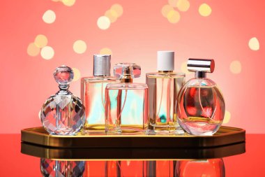 Ayna yüzeyinde birçok farklı parfüm şişeleri mercan zeminine karşı bulanık ışıklarla, yakın plan