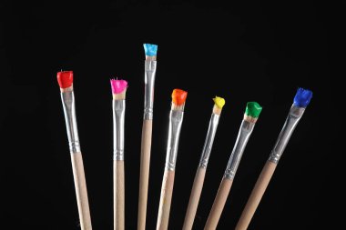 Siyah arkaplanda renk boyalı birçok fırça, yakın plan