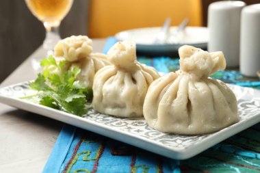 Gri masada kişniş ile servis edilen nefis khinkali, yakın plan.