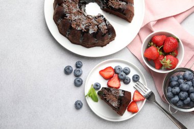 Açık gri desenli masada çilekli ve yaban mersinli nefis çikolatalı kek. Metin için boşluk